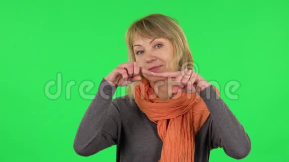 中年金发女子的画像是微笑用手指表示心意然后吹吻绿色屏幕视频的预览图