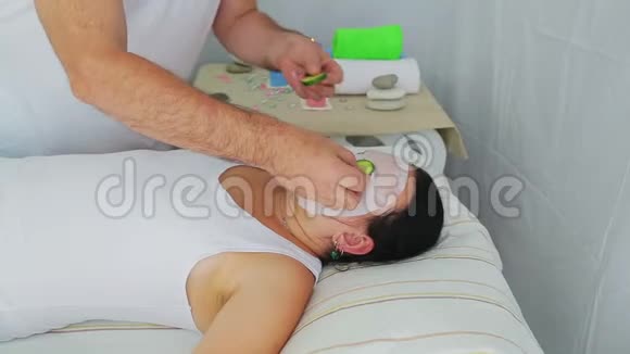 一位男性美容师把新鲜黄瓜放在水疗沙龙客户脸上视频的预览图