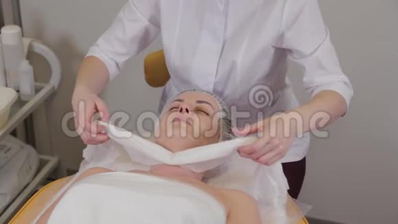 专业美容师女士用餐巾纸遮住病人的脸视频的预览图