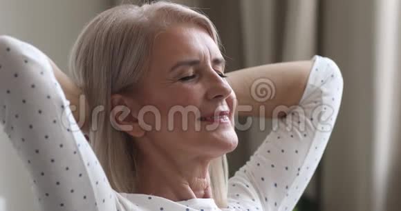 快乐梦幻的老妇人放松双手在家中视频的预览图