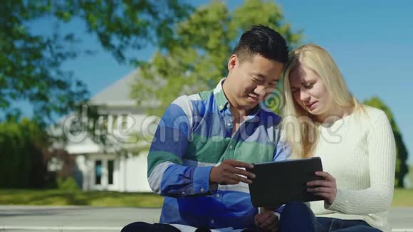 一个年轻的女人和一个男人在她家附近坐下好好享受药片视频的预览图