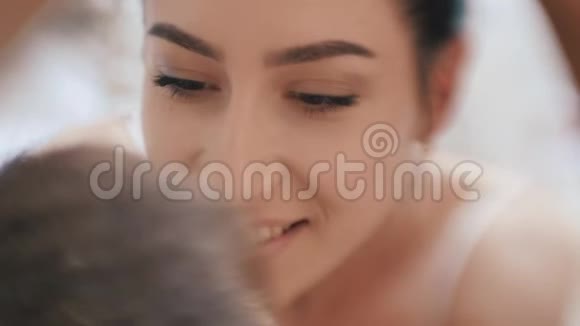 年轻快乐的一对恋人在家里的卧室里一起玩爱玩的妻子咬着微笑的丈夫的耳朵拥抱着视频的预览图