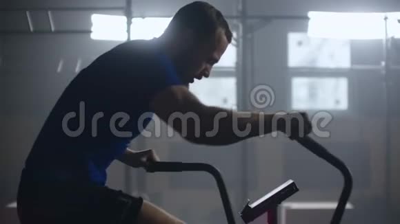 慢动作健身男子骑自行车在健身房旋转适合年轻女性健身车视频的预览图