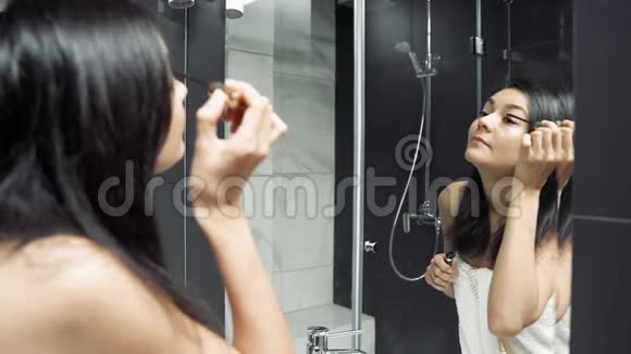 漂亮的年轻女人照镜子在浴室里用睫毛膏涂眼睛视频的预览图