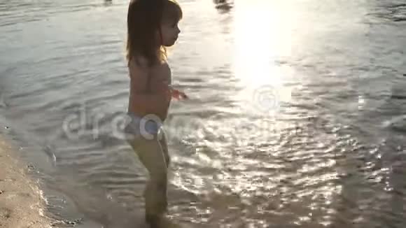 可爱的孩子在海滩上快乐地玩耍快乐的孩子在日落中沐浴在河流海洋湖泊上快乐童年概念视频的预览图