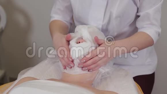 专业美容师女士用餐巾纸遮住病人的脸视频的预览图