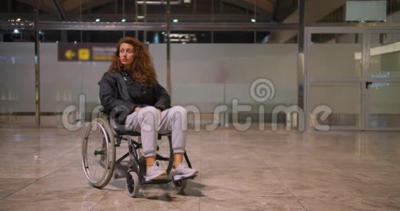 坐轮椅的年轻残疾女子在机场她一个人四处张望视频的预览图