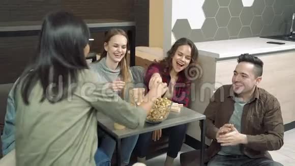 一群跨国朋友在家里的客厅里吃爆米花和玩块移除游戏视频的预览图