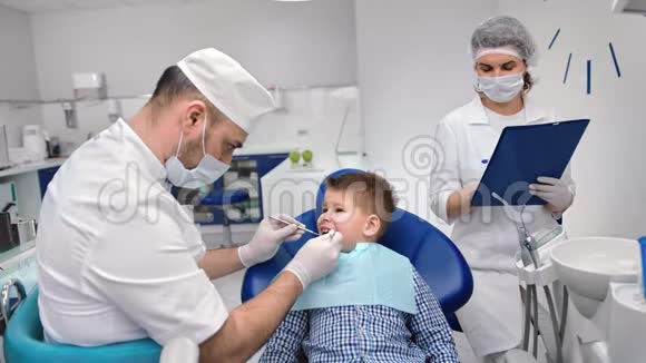 男医生和护士助理检查儿童口腔中型摄影机视频的预览图