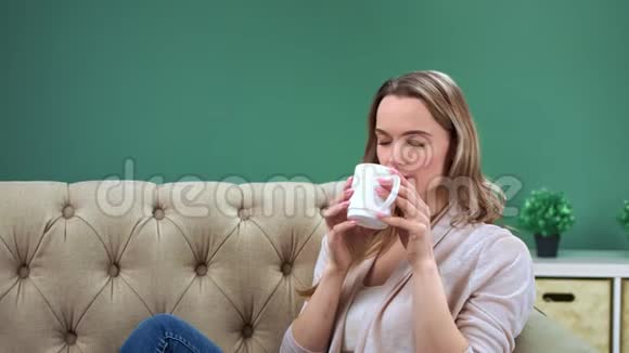 休闲的家庭女青年在舒适的沙发上喝茶红色摄像机中景视频的预览图