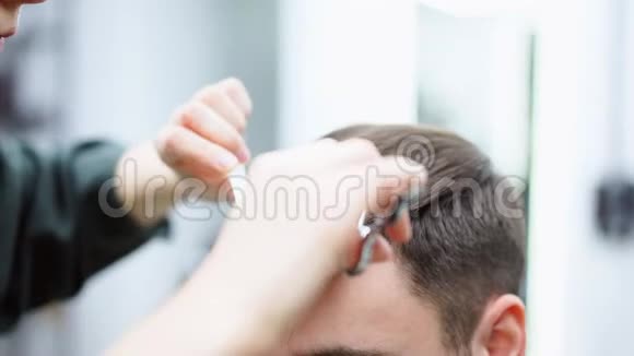 坐在理发店里的英俊蓝眼睛男人发型师理发师剪头发的女人女理发师视频的预览图