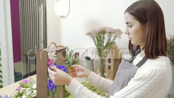 年轻女子花店在车间或商店里装饰鲜花和绿叶的礼品视频的预览图