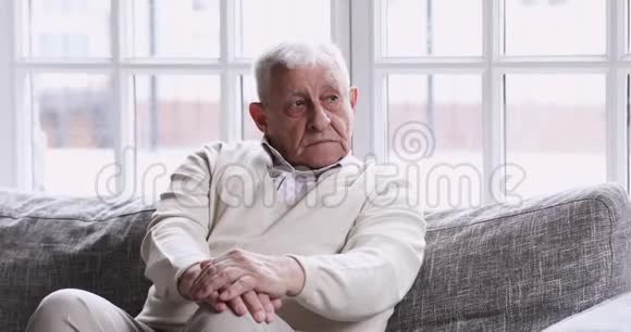 孤独的老爷爷独自坐在沙发上看着视频的预览图