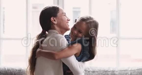 嬉戏的妈妈和可爱的小女儿在沙发上拥抱视频的预览图