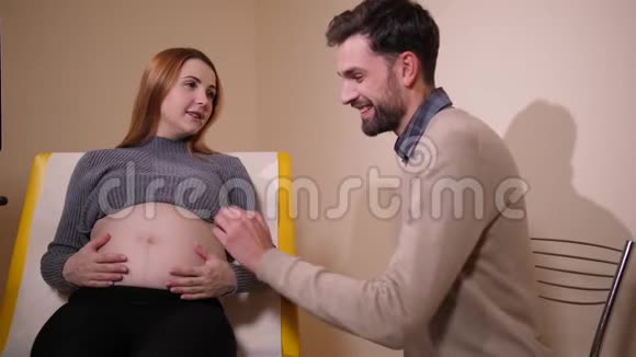 男人抚摸和亲吻孕妇的腹部视频的预览图