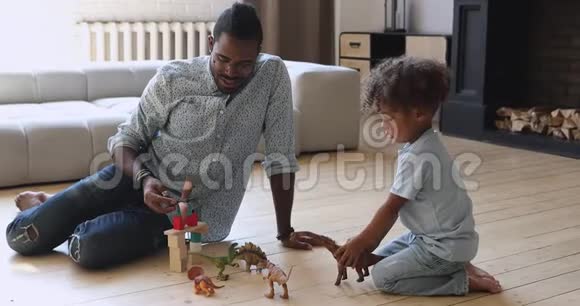 快乐年轻的非洲民族父亲和儿子玩恐龙视频的预览图