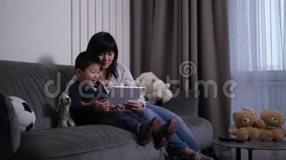 快乐的妈妈和儿子在平板电脑上看动画片视频的预览图
