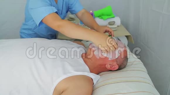 女性美容师从男人的脸上移除保湿面膜视频的预览图