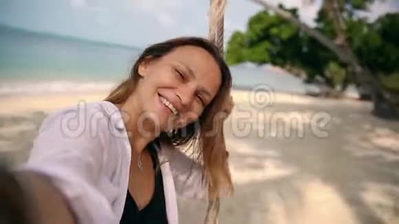 一个年轻女子在海滩上荡秋千时自拍视频的预览图