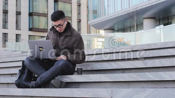 年轻的亚裔男程序员自由职业者在户外使用笔记本电脑视频的预览图
