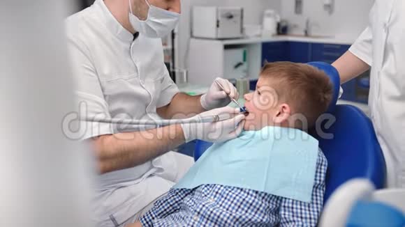 在牙科治疗期间男孩张开嘴坐着4k龙红相机视频的预览图