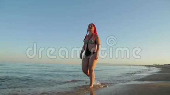 一个穿泳衣的女人沿着海滨散步视频的预览图