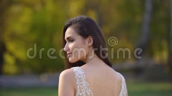 秋天公园里一位留着长发深褐色头发的美丽女人在阳光下摆姿势视频的预览图