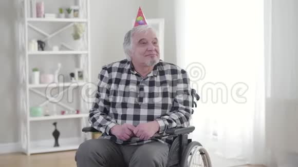 轮椅上快乐的老白种人从无效的标书中收到生日蛋糕的肖像快乐的成熟残疾人视频的预览图