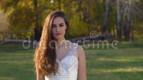 美丽的黑发新娘深深的目光是正确的并开始微笑在阳光明媚的秋天公园视频的预览图