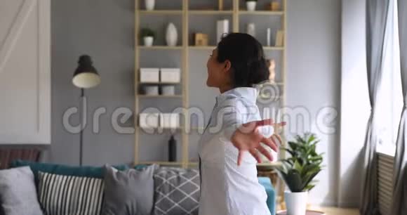 快乐的印度女人伸出双臂在客厅里旋转视频的预览图