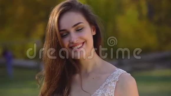秋天公园的阳光下留着长发深褐色头发的美丽女人的画像正在享受着欢乐视频的预览图