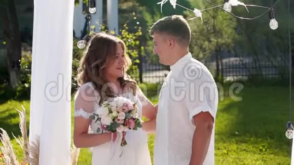 新娘和新郎在室外举行婚礼时互相亲吻朋友们在新婚夫妇的上方拍纸屑视频的预览图