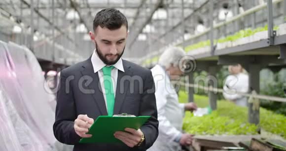 年轻的白种人留着胡子问成熟的模糊农学家然后转向写信息自信的审计员在工作视频的预览图