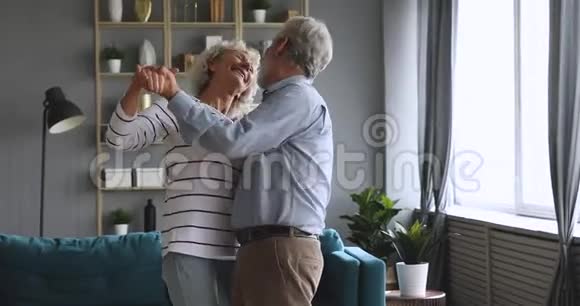 快乐无忧无虑的老人年长的祖父母外祖父母客厅里跳着华尔兹视频的预览图