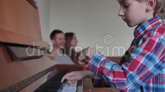 一个八岁的男孩和他的家人一起弹钢琴她的父母为她鼓掌视频的预览图