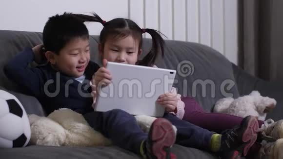 微笑的亚洲小孩在平板电脑上看搞笑视频视频的预览图