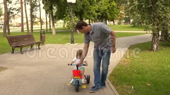 爸爸和他的孩子在户外玩耍孩子学会骑自行车幸福家庭和童年的概念父母和视频的预览图