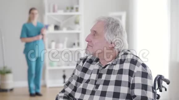 快乐的白种人白发苍苍的退休老人回头看着护士转向镜头摇着手势表示是视频的预览图