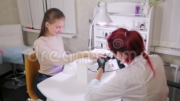 美容院的女美甲师在顾客的指甲上涂上紫色的凝胶视频的预览图
