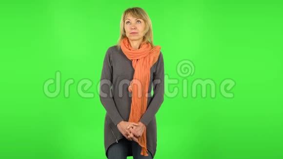 中年金发女人在做白日梦微笑着抬头看绿色屏幕视频的预览图