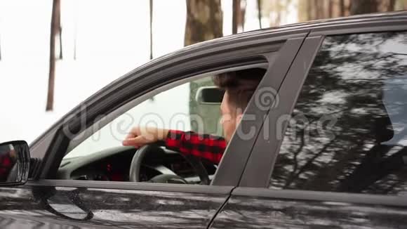 年轻迷人的白人男子坐在他的汽车车轮阳光明媚的冬天视频的预览图