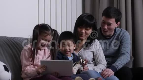 快乐的亚洲家庭在平板电脑上看动画片视频的预览图