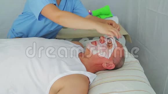女性美容师从男人脸上取出保湿面膜视频的预览图