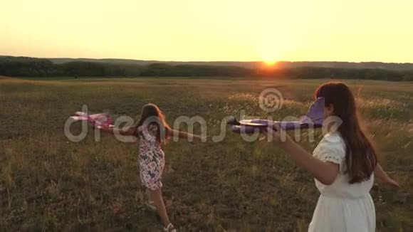 梦想飞翔快乐童年理念两个女孩在日落时玩玩具飞机太阳背景下的孩子们视频的预览图