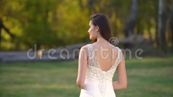 美丽的黑发新娘深深的目光是正确的并开始微笑在阳光明媚的秋天公园视频的预览图