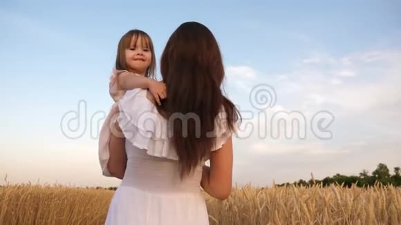 妈妈和小女儿正在阳光下的一片成熟的麦子上玩耍母亲带着孩子走在麦地里视频的预览图