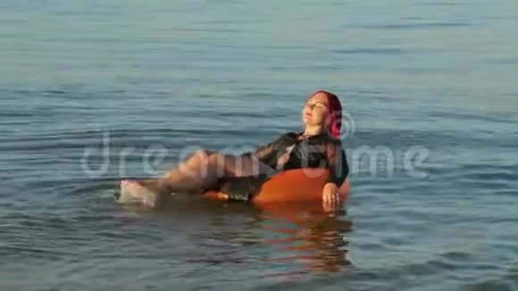 一个穿着泳衣穿着红发的女人在游泳圈晒太阳视频的预览图