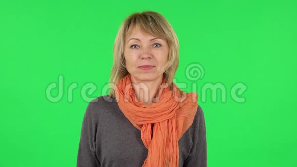 中年金发女人的肖像正在挥手并在这里展示手势绿色屏幕视频的预览图
