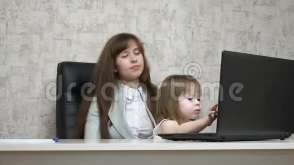 疲惫的母亲和她的小女儿在办公室的电脑上工作从事商业工作的妇女视频的预览图