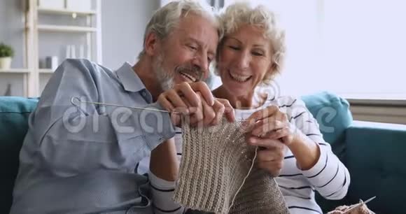 快乐的祖父母夫妇在家里一起编织围巾玩得很开心视频的预览图